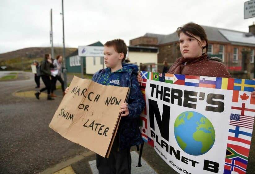 Finlay Pringle, pictured with his sister Ella in 2019. They are each holding protest signs, reading "March now or swim later", and "There is no planet B".