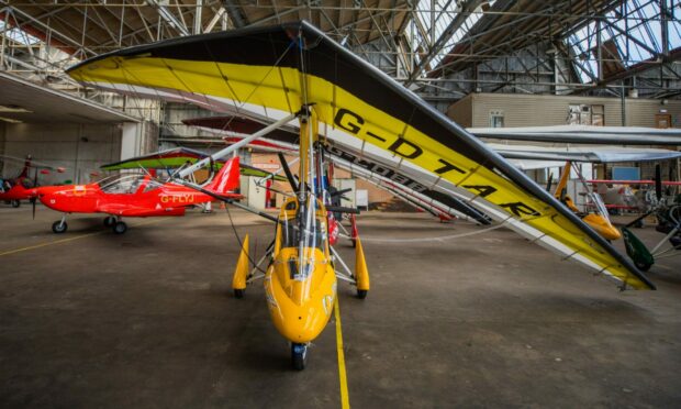 A yellow flexwing microlight in the Scottish Aero Club hangar.