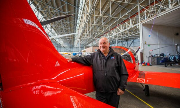 Kevin Whitehead from Alba Airsports standing next to a red fixed wing microlight.