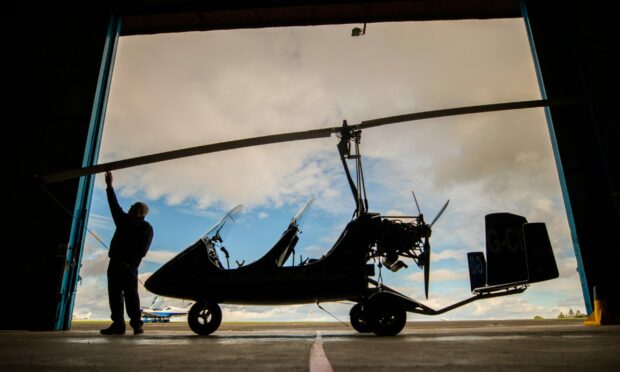 A silhouette of Kevin Whitehead from Alba Airsports checking the rotor blades of his gyrocopter.