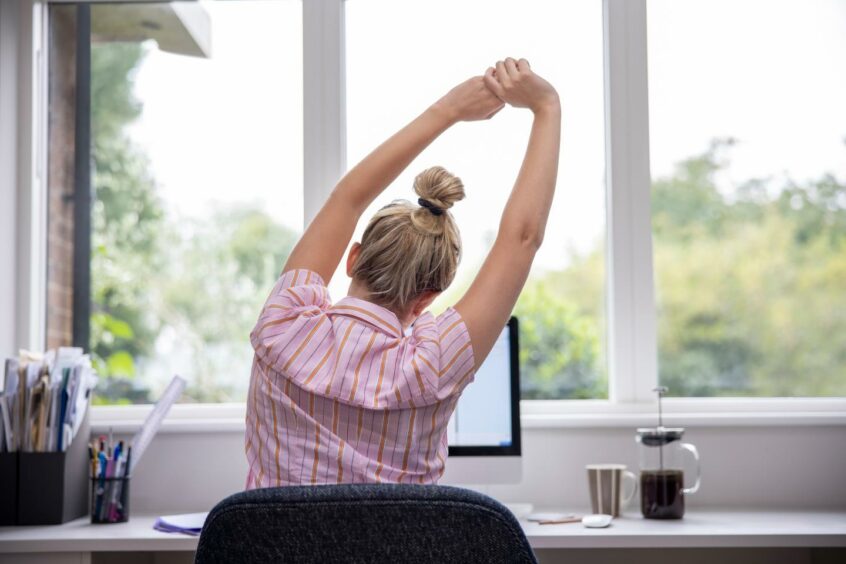 A woman stretching while sitting in a chair.