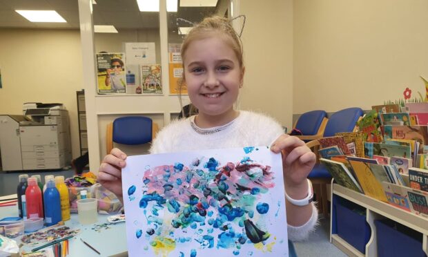 A girl holds up a painting created during a Teapot Trust art therapy session