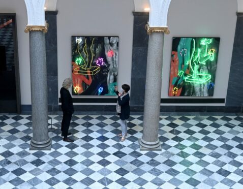 An interior picture of Aberdeen Art Gallery with two people in front of paintings