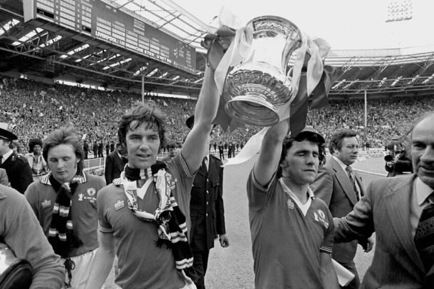 Martin Buchan holds aloft the FA Cup while at Manchester United