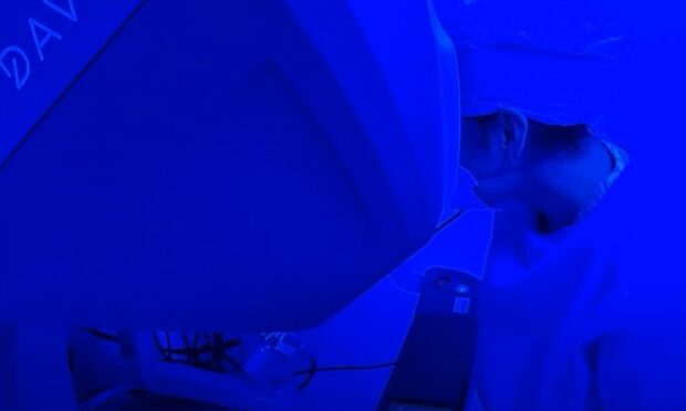 Immersed in the blue lights of the operating theatre, Ana Da Silva looks at one of the robot surgery consoles.