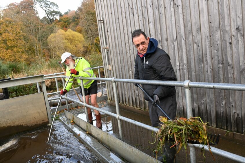 Volunteers and directors Clive Potter and Rick Vaughan cleaning debris from the intake of the turbine.