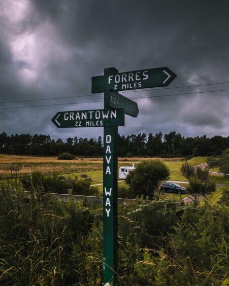A signpost on the Dava Way showing 22 miles to Grantown and 2 miles to Forres