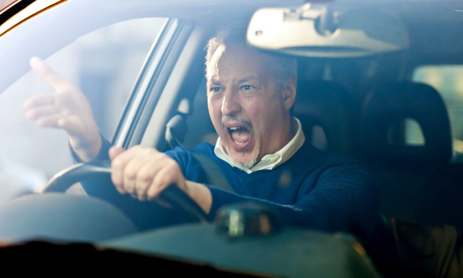 A driver reacts angrily while in a car