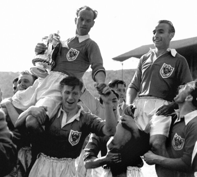 Stanley Matthews, while playing for Blackpool, is chaired from the Wembley pitch with team captain Harry Johnson (holding the cup) after his side claimed victory over Bolton by four goals to three in the FA Cup final.