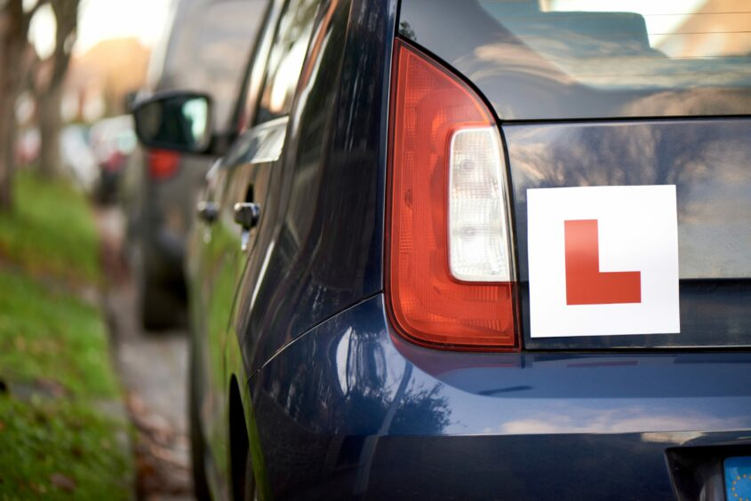 The back of a car with an L-plate on it.