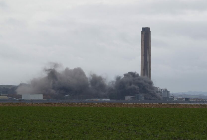 The plant seen from a distance, with smoke billowing upward, as the boiler house is demolished in February of 2021.