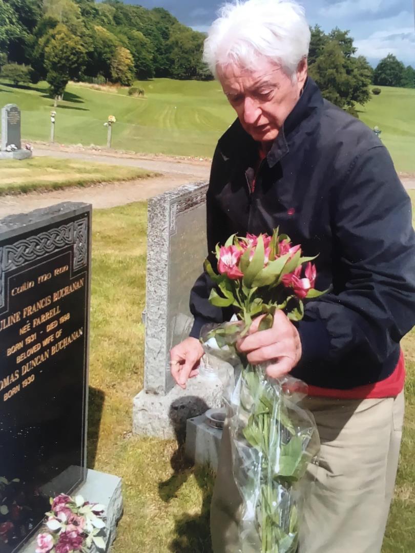 Tom Buchanan laying flowers on his wife Pauline's grave in Kilvean cemetery, Inverness.
