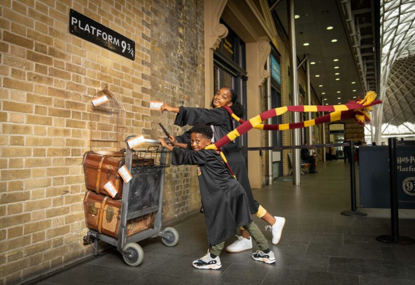 King's Cross is a "very, very romantic place" for JK Rowling. Here, Blake, 5, and Soraya, 10, pose with the Harry Potter Platform 9 ¾ trolley at King's Cross Station. Picture: PinPep/Shutterstock.