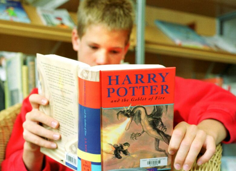 A young boy reads a Harry Potter book.
