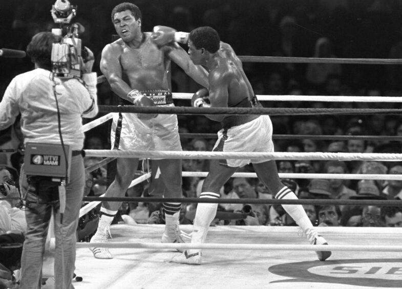 Muhammad Ali in the ring for the last time, as Trevor Berbick hits Ali and a cameraman records the moment.