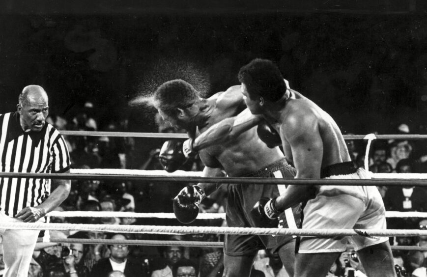 Perspiration flies from the head of George Foreman as he takes a right from challenger Muhammad Ali in the seventh round in the match dubbed the Rumble in the Jungle in 1974.