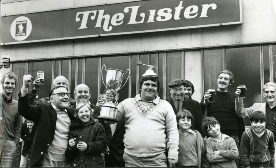 Jocky Wilson and members of the public with the trophy outside the Lister Bar, after driving through the night following his victory. Picture: DCT Media.