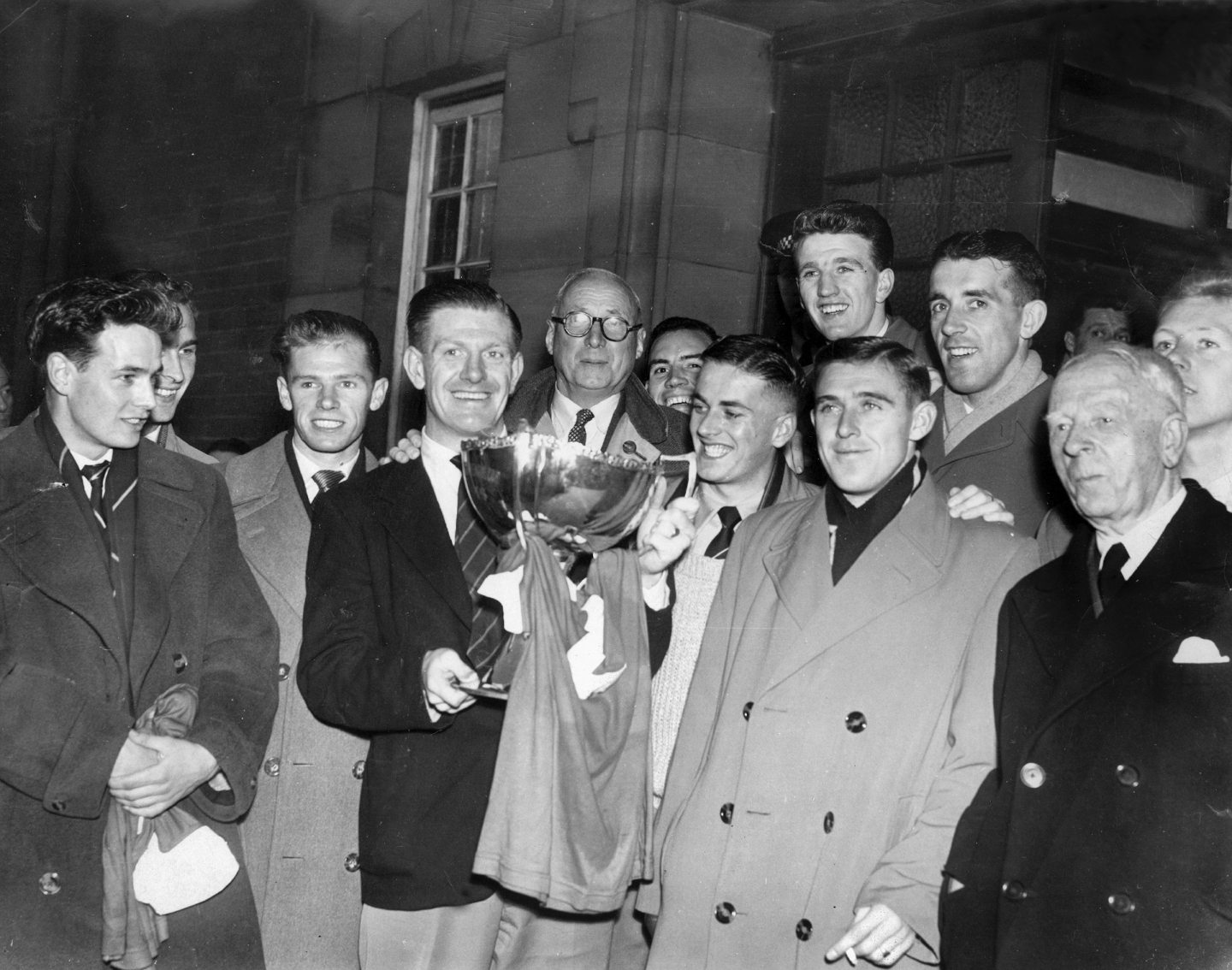 Captain Jimmy Mitchell still has his jersey attached to the League Cup as the players celebrate the 1955 triumph.