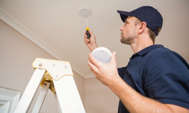 A workman installing a smoke alarm