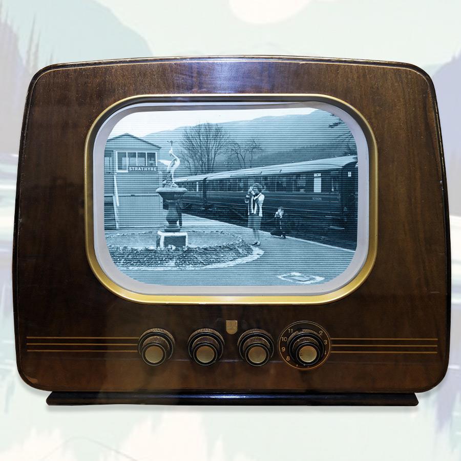 An old wooden TV with a picture of a woman on railway platform