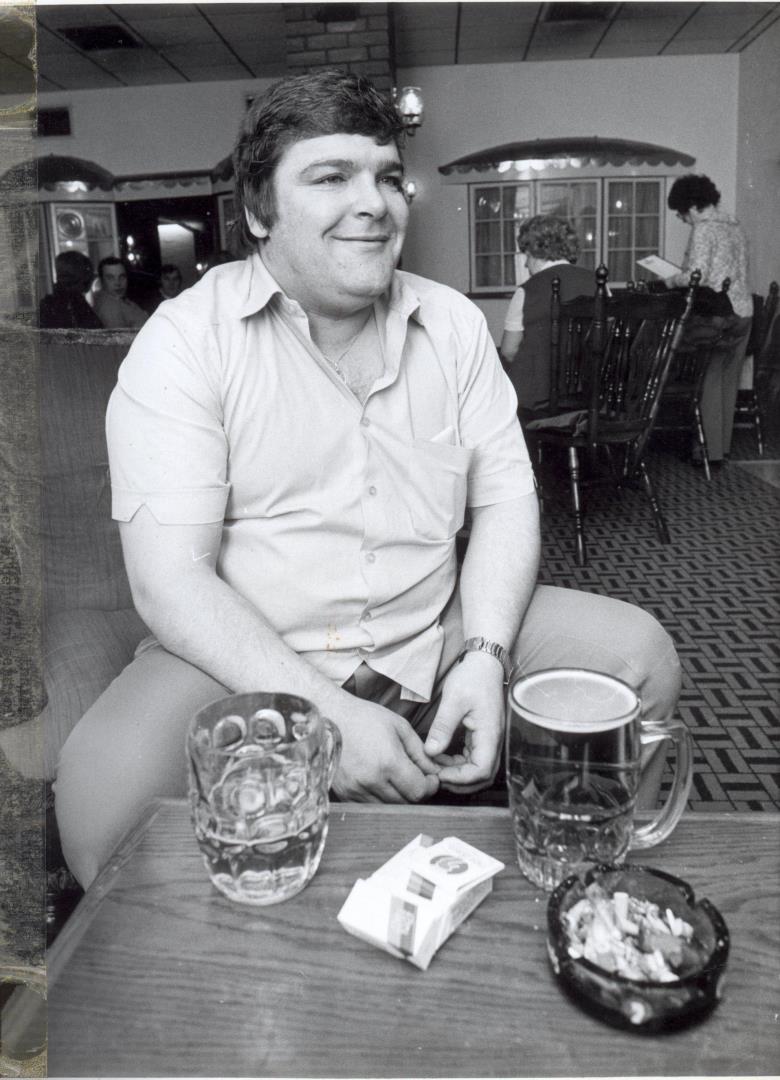 Jocky Wilson sits at a with a table of pints and cigarettes