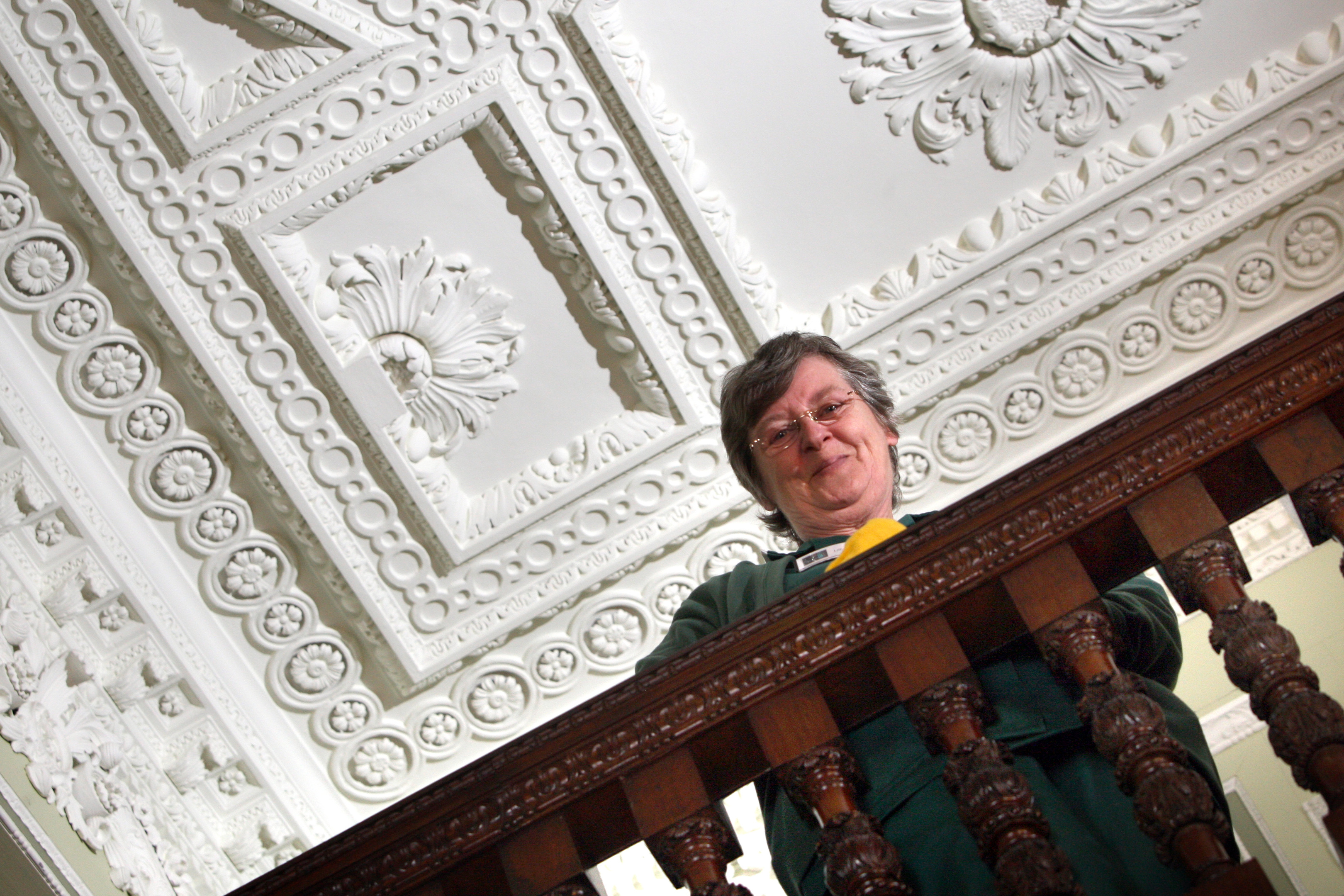 Lillian Lamond from the house keeping team with the Syrian-inspired front stair ceiling cornice and plaster work behind her.