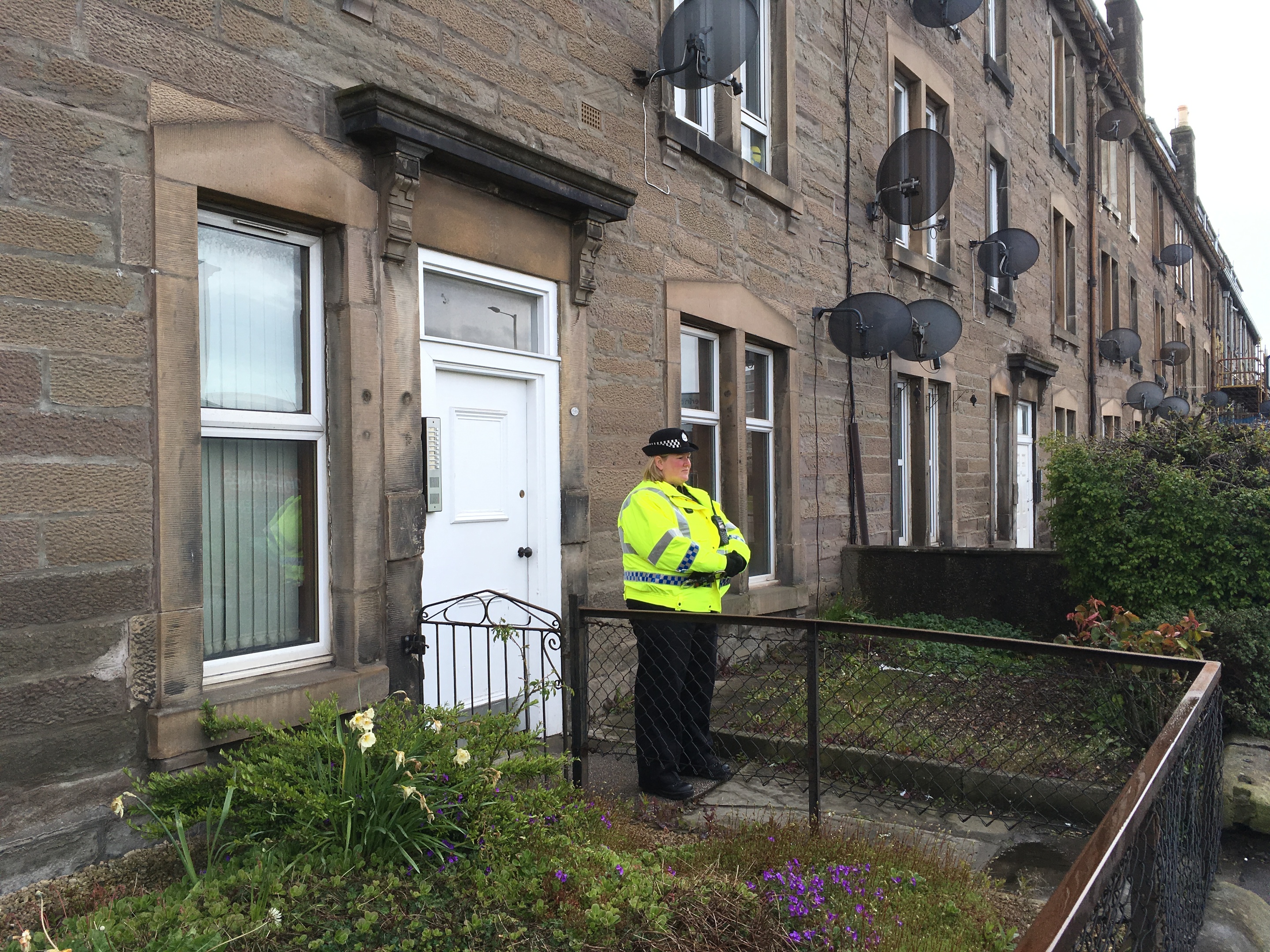 Police stand guard outside flat where woman was found dead.