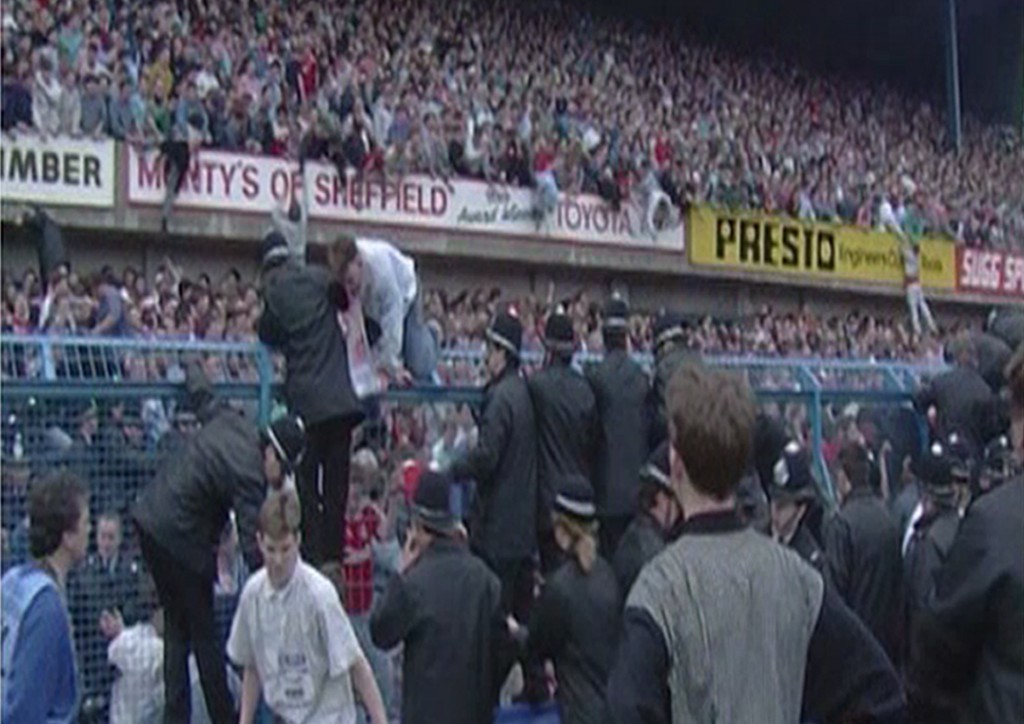 People climbing over the fence at the Leppings Lane end of Hillsborough Stadium during the FA Cup semi-final between Liverpool and Nottingham Forest.