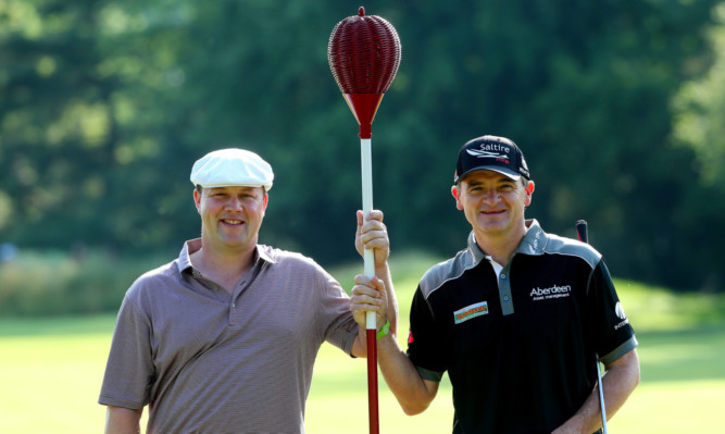 Scots Chris Doak, left, and Paul Lawrie take a break from preparing for their first round to pose with a wicker basket flag stick.