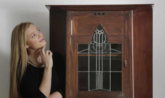 Arts graduate Charlotte Roberts with the long lost music cabinet designed by Charles Rennie Mackintosh.