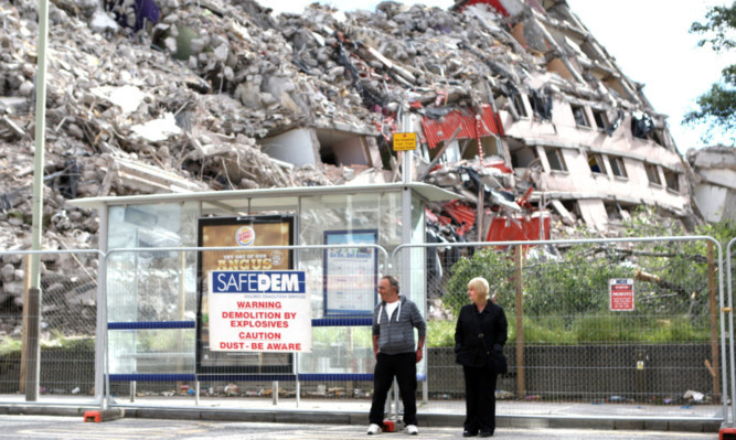 Down to Earth: people waiting for a bus near the mass of rubble in Dundee.