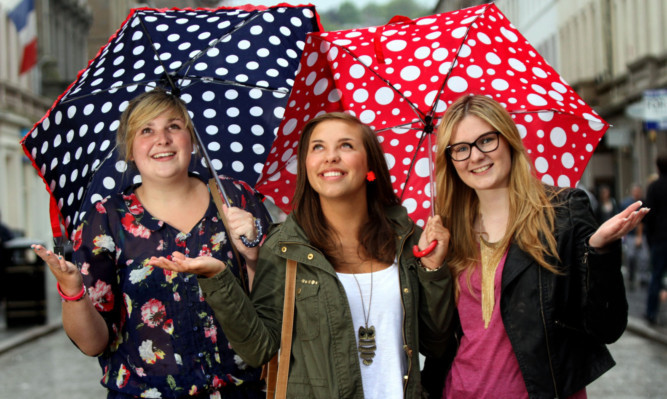 Adreanne Walker, Chelsea Wier and Eryn Pattie, from Dundee, shelter from the summer rain.