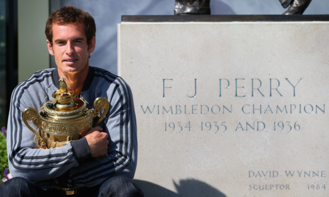 Andy Murray posing with the winner's trophy beside a statue of Fred Perry at Wimbledon on Monday.