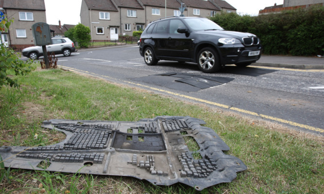 Debris from a damaged car beside the speed humps.