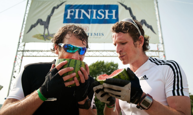 Mark Beaumont and Bruce Duncan tuck into the now traditional melon at the finish line.