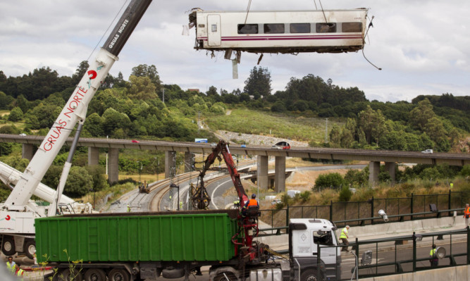 A derailed train car is lifted by a crane at the site of a train accident in Santiago de Compostela in Spain.