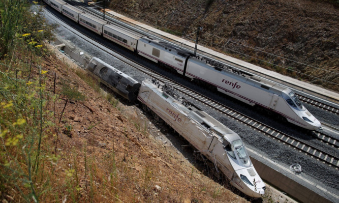 The first Madrid-Ferrol train service since the accident passes next to the wreckage of the previous one