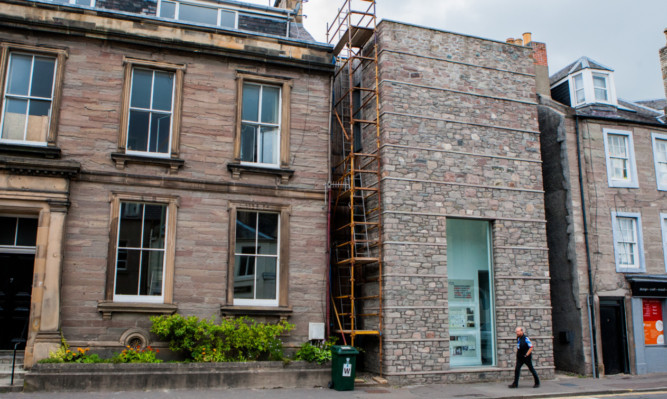 Scaffolding divides the two buildings at the centre of the row.