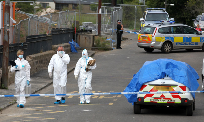 Police forensics examine the scene on Auldhouse main street.