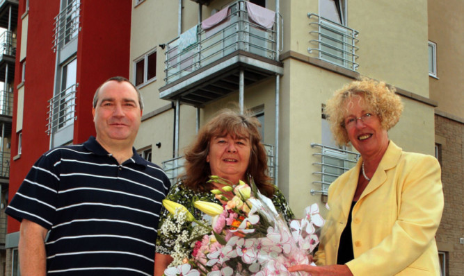 Housing minister Margaret Burgess presents flowers to new tenants Stewart and Helen Mackie.