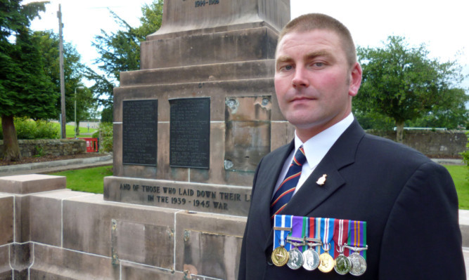 Steven Reid beside the memorial in Milnathort, still missing some of its bronze plaques.