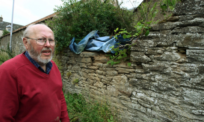 Ian Glenn beside the damaged wall at his home in Liff.
