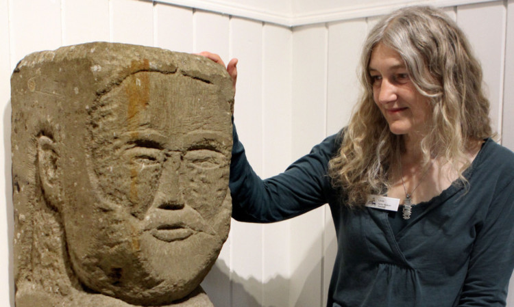 Linda Fraser, senior museum assistant at Montrose Museum, with one of the large stone heads carved by Adam Christie.