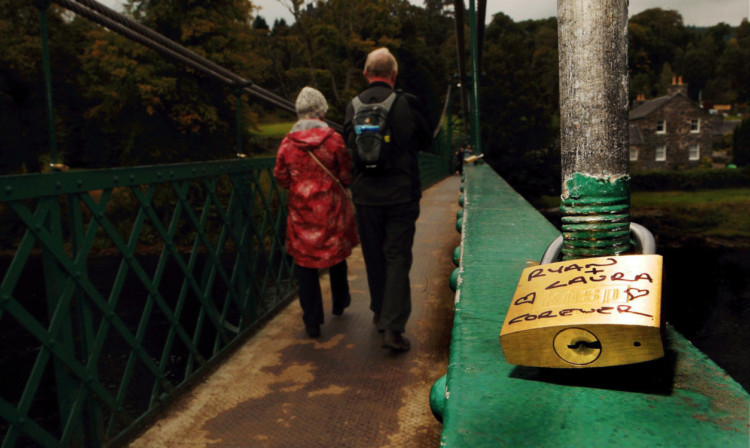 A couple crossing the love locks bridge.
