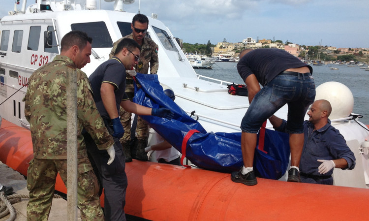 The body of a drowned migrant is  unloaded from a Coast Guard boat in the port of Lampedusa, Sicily.