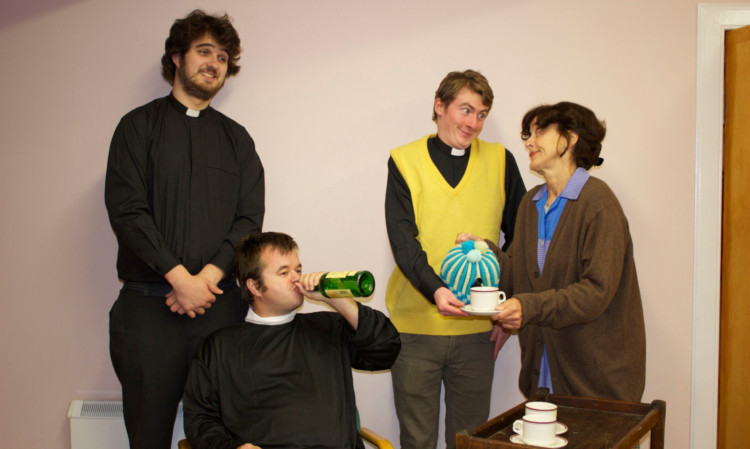 Mrs Doyle (Margaret MacKenzie) passing out the tea to Father Ted (Craig Waters), Father Jack (Ewan Howells) and Father Dougal (Kenneth Fairclough).