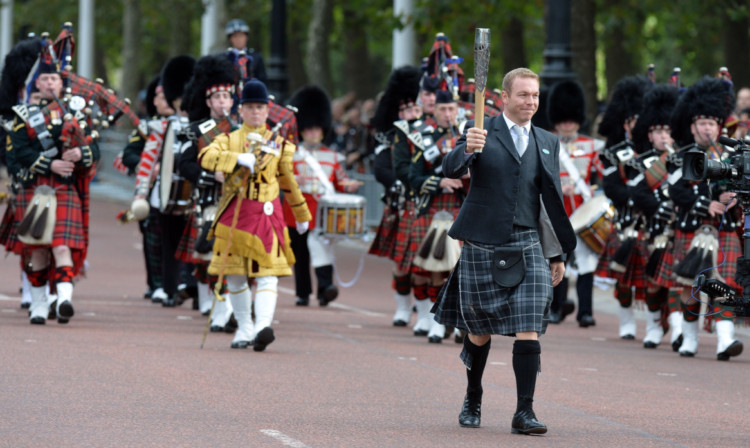 Sir Chris Hoy carries the Commonwealth Games baton along The Mall to Buckingham Palace in central London.