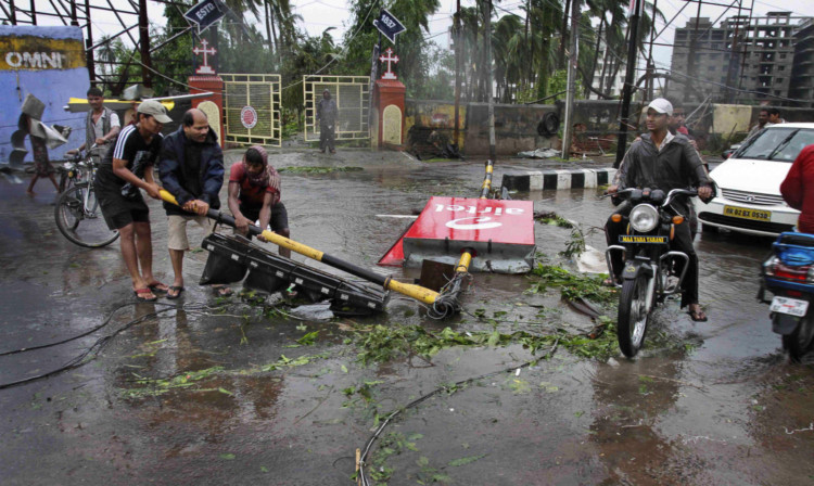 Locals remove a traffic signal pole fallen during Cyclone Phailin from a road in Berhampur, India.