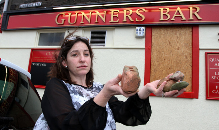 Landlady Jacqueline Long with the rocks that were thrown at the windows.