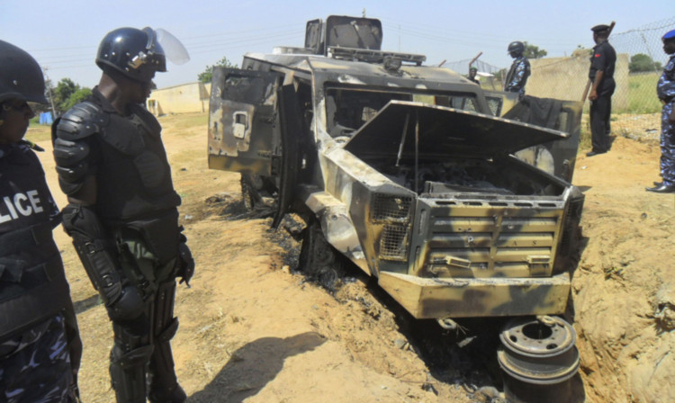 Police at a burnt-out army personnel carrier following an attack by Boko Haram in Damaturu, Nigeria. The Islamic extremists have also stormed a college, killing around 40 students.